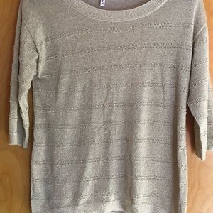 Cream sweater with gold accents.